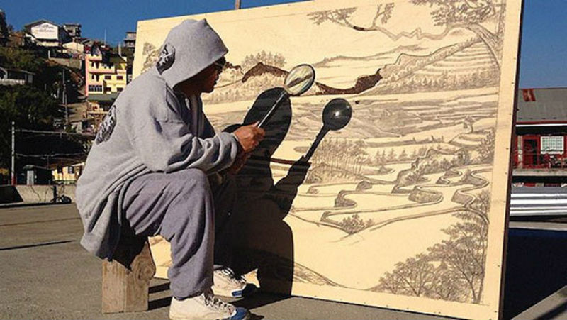 Художник рисует при помощи лупы и солнечного света